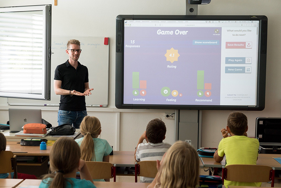 children and educator in classroom with smartboard